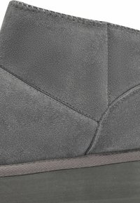 Bottine en daim gris avec une finition texturée, ornée d'accents cousus et dotée d'une semelle en caoutchouc plate pour une traction et une durabilité optimales.