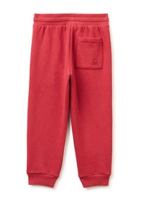 Červené tepláky vyrobené z měkké bavlněné tkaniny, s elastickým pasem, zúženými nohavicemi a zadní kapsou s jemným logem.