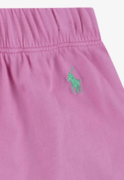 Rosa shorts med elastisk midja och texturerad yta, med en grön broderad logotyp av en liten häst på sidan.