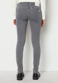 Harmaat slim-fit farkut, joissa on keskikorkea vyötärö, viisi taskua ja pieni merkkilappu takana. Sileä rakenne.