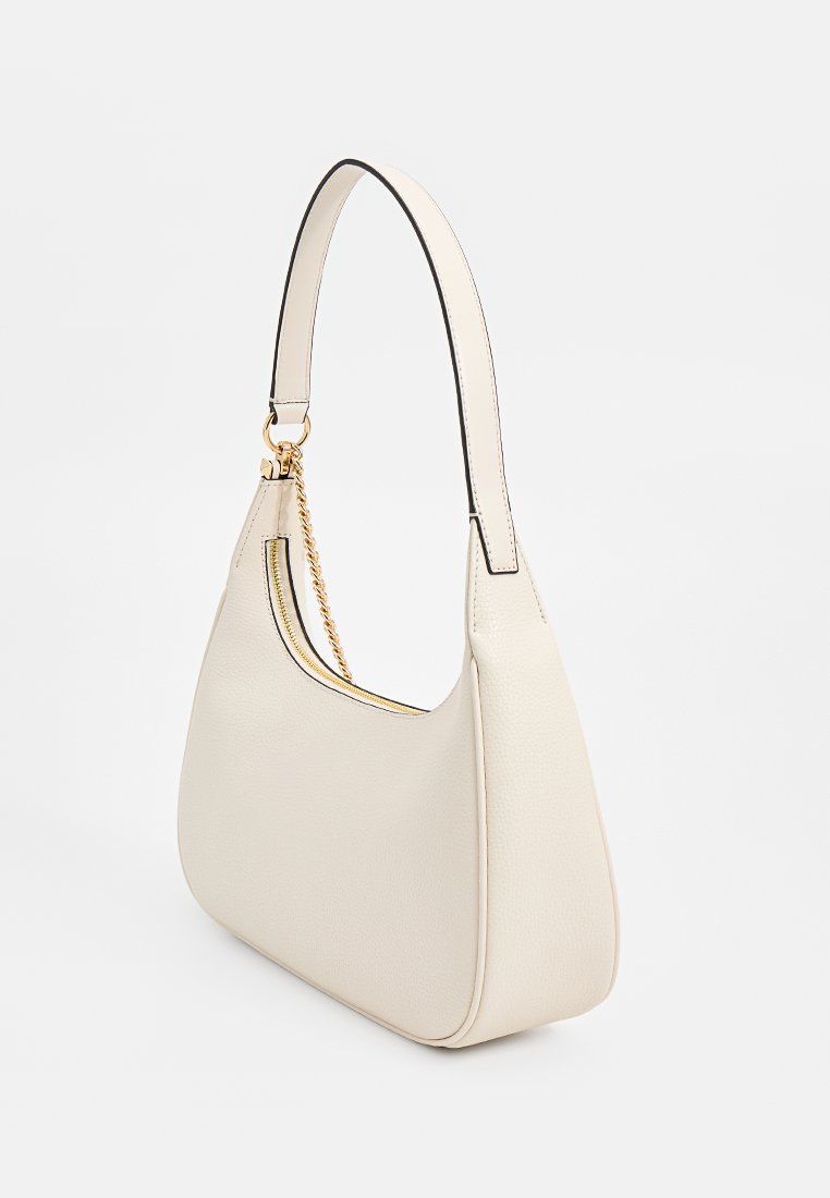 Sac à main en cuir couleur crème avec une silhouette courbée, des bords noirs et une courte bandoulière accentuée par une chaîne. Fini texturé, design minimaliste.