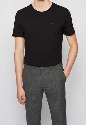 Czarna bawełniana koszulka z okrągłym dekoltem i subtelnym logo "BOSS", zestawiona z szarymi spodniami w kratę.