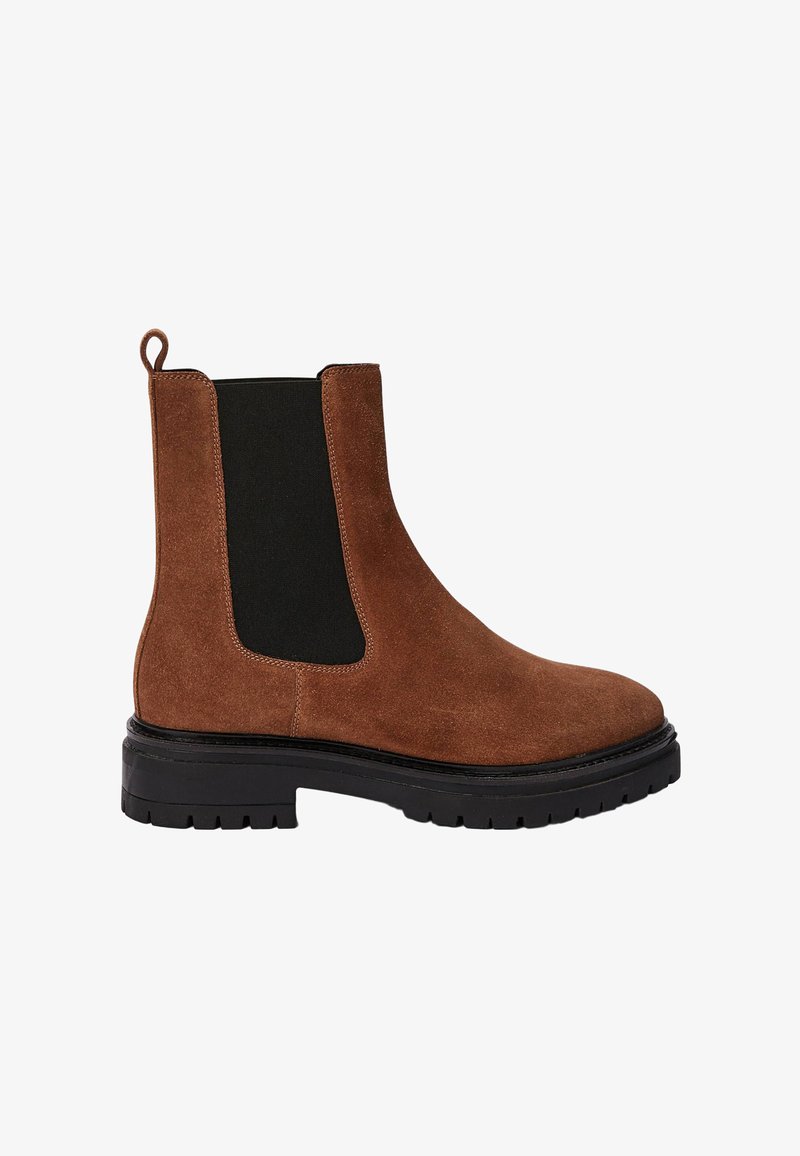 Botte Chelsea en daim marron avec des panneaux élastiques noirs sur les côtés, bout arrondi et semelle en caoutchouc noir épaisse. Présente une languette à l'arrière.