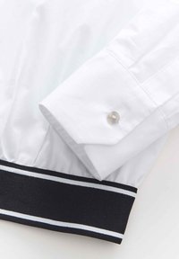 White dress shirt cuff with a button, featuring a black ribbed cuff band with white and light blue stripes. Smooth fabric texture.