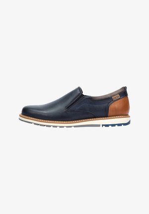 Chaussure slip-on en cuir marine avec des accents en cuir marron, semelle blanche, coutures contrastées et bout arrondi. Comprend des panneaux latéraux élastiques pour un ajustement optimal.
