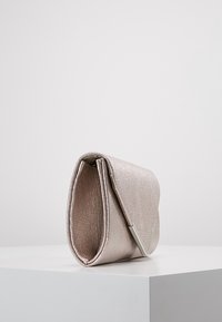 Metallinen ruusukultainen käsilaukku, sileä pinta, taitettu muotoilu, hopeiset yksityiskohdat, kompakti malli, jossa on erottuva reunaohje.