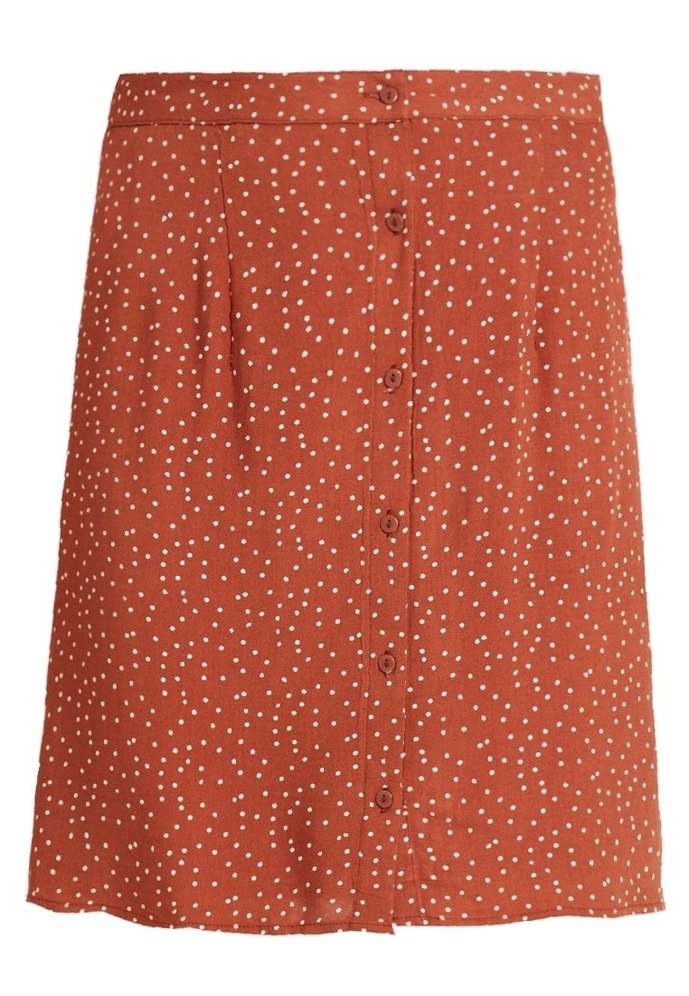 Jupe longueur genou de couleur rouille avec des pois blancs et une fermeture boutonnée à l'avant.