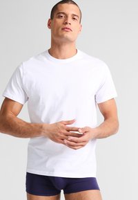 Witte katoenen t-shirt met een ronde hals en korte mouwen, met een klassieke pasvorm en een gladde textuur. Draag het met donkerblauwe onderkleding.