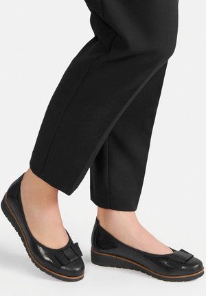 Ballerine nere in vernice con finitura testurizzata, dotate di un dettaglio a fiocco sulla punta e suola in gomma bassa per comfort e aderenza.