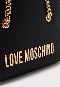 Black handbag with gold chain straps and raised gold "LOVE MOSCHINO" logo on front.
