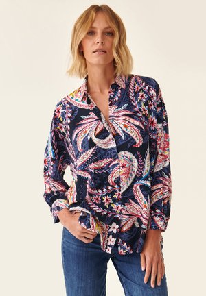 Camisa de botones con un fondo azul marino y vibrantes patrones florales y de cachemira en rosa, rojo y verde. Mangas largas con detalle en los puños.