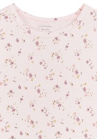 Rosa kurzärmliges Oberteil aus Bambusviskose, das mit einem floralen Muster in Lila- und Gelbtönen versehen ist. Weiche, glatte Textur.