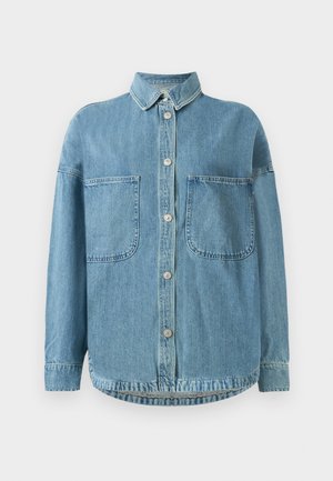 Chemise en denim bleu clair, dotée d'un devant à boutons, d'un col, de deux grandes poches poitrine et d'une ourlet arrondi. Le matériau a une finition texturée.