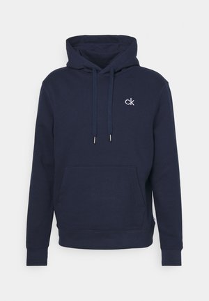Marinblå hoodie i mjukt material med känguruficka, snoddar och en liten vit logotyp på bröstet.