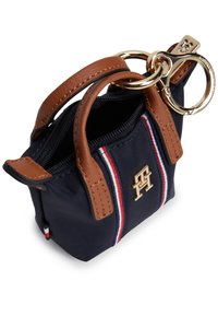 Μικρό τσαντάκι από ναυτικό καμβά με καφέ δερμάτινες λαβές, χρυσό λογότυπο, χρυσά εξαρτήματα και κόκκινες και λευκές ρίγες ως διακοσμητικά στοιχεία. Άνοιγμα με φερμουάρ στο πάνω μέρος.