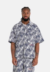 Korte mouw shirt van geweven stof met een marineblauw en wit abstract patroon, met twee voorkeuzepockets en zilveren knopen.