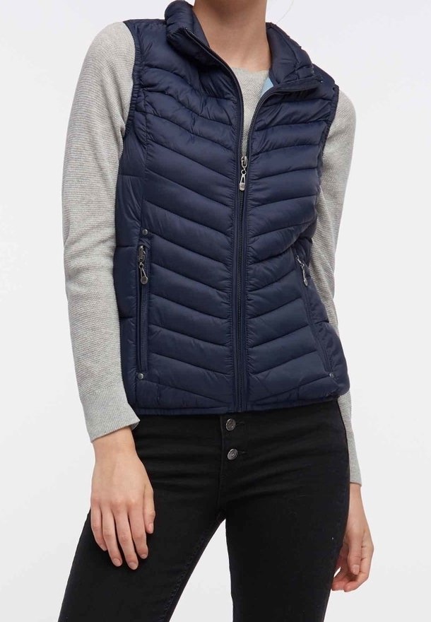 Marineblauwe gewatteerde bodywarmer met een ritssluiting aan de voorkant, een hoge kraag en twee voorzakken met rits. De bodywarmer heeft een doorgestikte structuur en een getailleerde pasvorm.