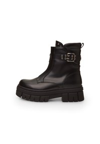 Stivale in pelle nera alla caviglia con suola spessa, dotato di zip laterale, fibbia decorativa e dettagli in borchie sulla fascia superiore.