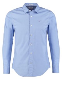 Chemise bleu clair à manches longues, coupe ajustée, boutonnée, avec col et petit logo brodé sur la poitrine gauche.