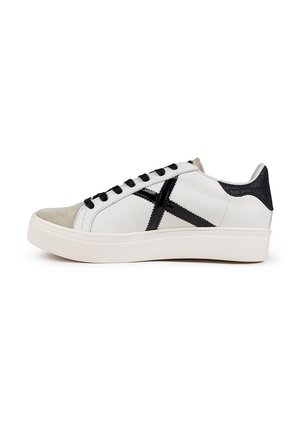 Sneaker in pelle bianca con accenti neri e punta in suede. Presenta lacci neri, un tallone testurizzato e una spessa suola in gomma bianca.