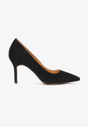 Escarpin noir en daim à talon haut avec un bout pointu, une silhouette épurée et un fin talon aiguille. L'intérieur est doté d'une doublure beige.