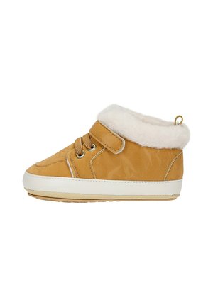 Zapatilla marrón para niño pequeño con forro de piel blanca, tira de velcro, cordones y suela de goma blanca.