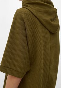 Prenda con capucha de color verde oliva que presenta un tejido texturizado en un patrón de panal, con mangas cortas y un diseño de ajuste relajado.
