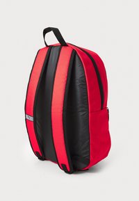 Rucsac roșu și negru, cu spate căptușit, bretele ajustabile și un buzunar frontal cu fermoar. Țesătură netedă, cu decorațiuni minime și detalii ale logo-ului.