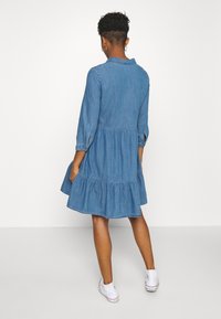 Jeansklänning med ett lagerdesign, långa ärmar och krage. Ljusblå färg med en något avslappnad passform.