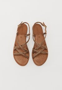 Sandales en cuir marron avec des lanières tressées, semelle perforée et bride de cheville ajustable avec des accents en or.