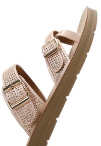 Lichtroze sandaal met twee banden en gouden gespen, versierd met rhinestones, en een textuur crèmekleurige zool.