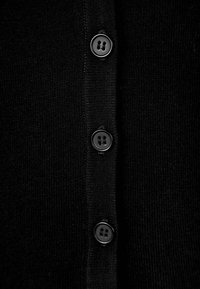 Black knitted cardigan featuring a row of five black buttons along the front. Smooth texture with a classic, simple design.