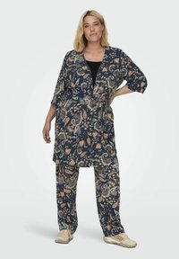 Gėlėmis dekoruotas tamsiai mėlynas kimono stiliaus chalatas su raišteliu talijoje, derinamas su atitinkamomis laisvomis kelnėmis. Audinys atrodo glotnus ir lengvas.