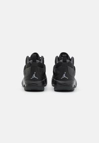 Ett par svarta träningsskor med synlig Air Jordan-logotyp på hälarna, visade bakifrån på en vit bakgrund.