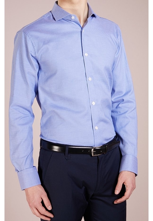 Camicia da uomo a maniche lunghe di colore azzurro, con motivo a quadri, colletto button-down e bottoni bianchi, abbinata a pantaloni blu navy e una cintura nera.
