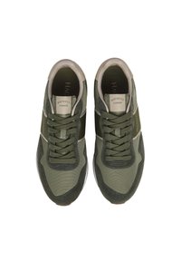 Zapatillas deportivas verdes con una combinación de malla texturizada y tela lisa. Incluyen cordones, suela de goma y marca en la lengüeta.