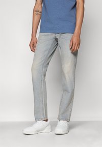 Lys blå denim jeans med rett ben, falmet tekstur og fem-lomme design. Brukes med en blå t-skjorte og hvite sneakers.