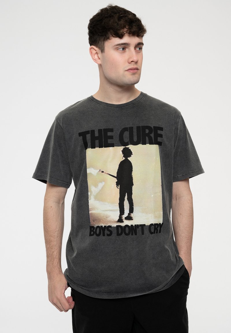 Gray, short-sleeve t-shirt made of cotton, featuring a graphic of a silhouette holding a guitar, with text "THE CURE BOYS DON'T CRY" below.