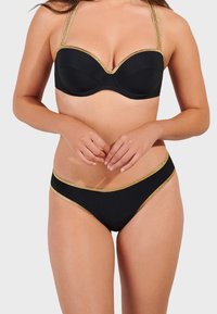 Svart bikiniset med en strukturerad bh-top med guldkanter, justerbara band och matchande bikiinibyxor med gulddetaljer längs kanterna.