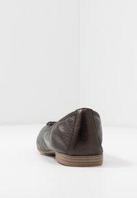 Ballerine in pelle marrone scuro con tacco basso, punta arrotondata e bordo elasticizzato. Il motivo della superficie testurizzata arricchisce il design complessivo.