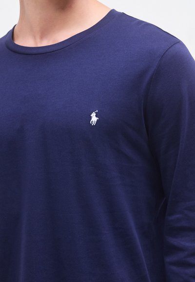 Camiseta de manga comprida azul-marinho feita de tecido macio, com decote redondo e um pequeno logótipo branco bordado no peito.