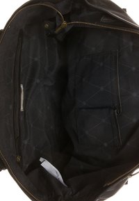 Interiér černé látkové tašky s kapsou na zip, plochou kapsou a geometrickým vzorem. Obsahuje metalický zip a měkkou texturu.
