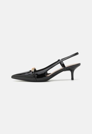 Zapato de tacón slingback de charol negro con punta afilada, tacón pequeño y acento decorativo en tono dorado. Presenta lados abiertos y un diseño elegante.