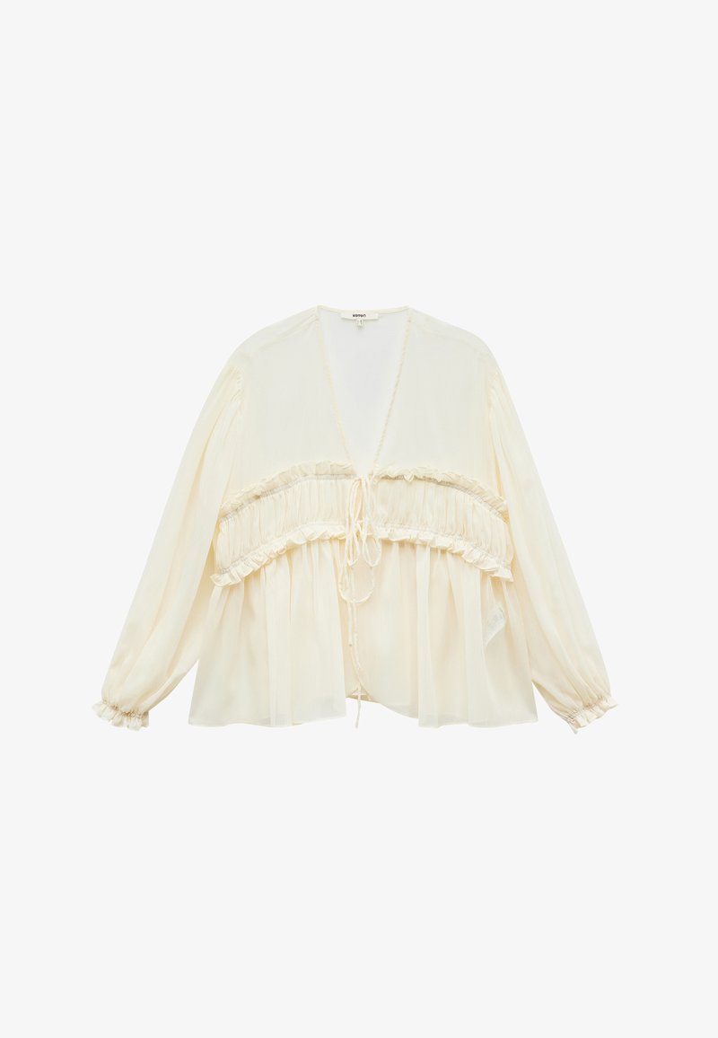 Blouse crème avec de longues manches bouffantes, taille froncée et fermeture à nouer à l'avant. Texture transparente et silhouette décontractée.