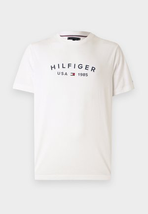 Bijela pamučna majica s okruglim izrezom, kratkim rukavima i središnjim logotipom koji glasi "HILFIGER USA 1985" u tamnoplavoj boji s crvenim i plavim grbom.