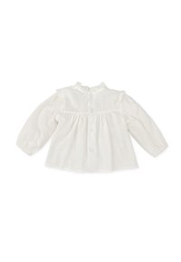 Blusa de algodón blanca con mangas largas, cuello fruncido y cierre de botones. Presenta un delicado encaje en los hombros y los puños.