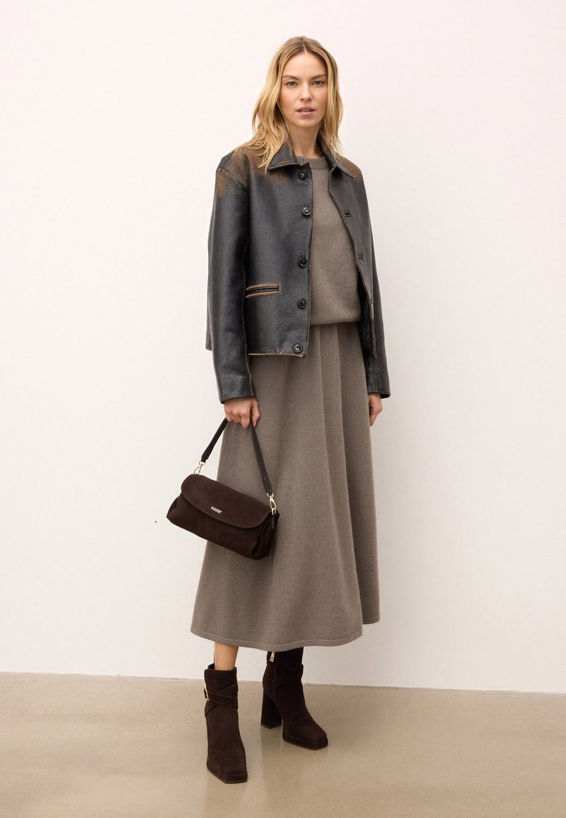 Czarna skórzana kurtka z jasnym przeszyciem, szary sweter dzianinowy, szara spódnica maxi, ciemnobrązowa zamszowa torebka, oraz brązowe botki na stabilnym obcasie.