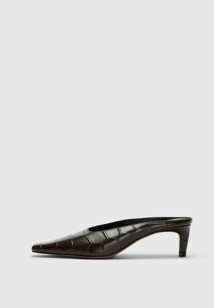 Zapato mule de cuero marrón oscuro con tacón bajo de tipo kitten y textura de cocodrilo, mostrado de lado sobre un fondo liso y claro.