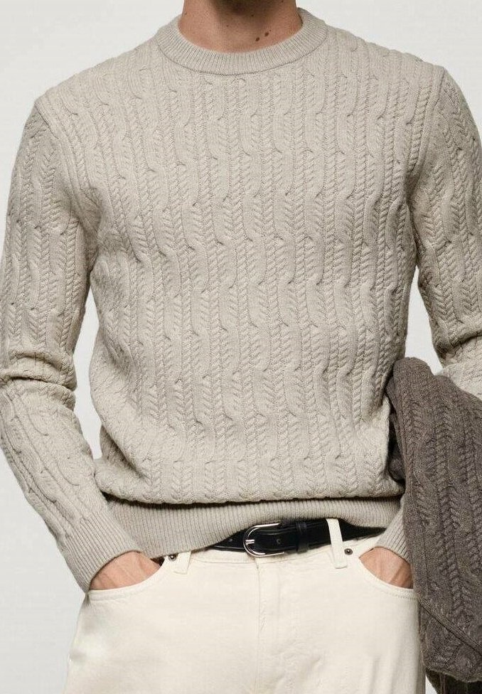 Cable-knit sweater in light beige, round neck, ribbed cuffs and hem, featuring a textured pattern; model holds a darker gray sweater.