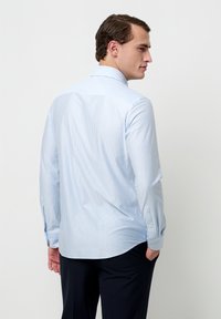 Lichtblauw-wit gestreept shirt met lange mouwen, voorzien van een standaardkraag, knoopmanchetten en een klassieke pasvorm. Heeft een afgeronde zoom en is gemaakt van katoenen stof.